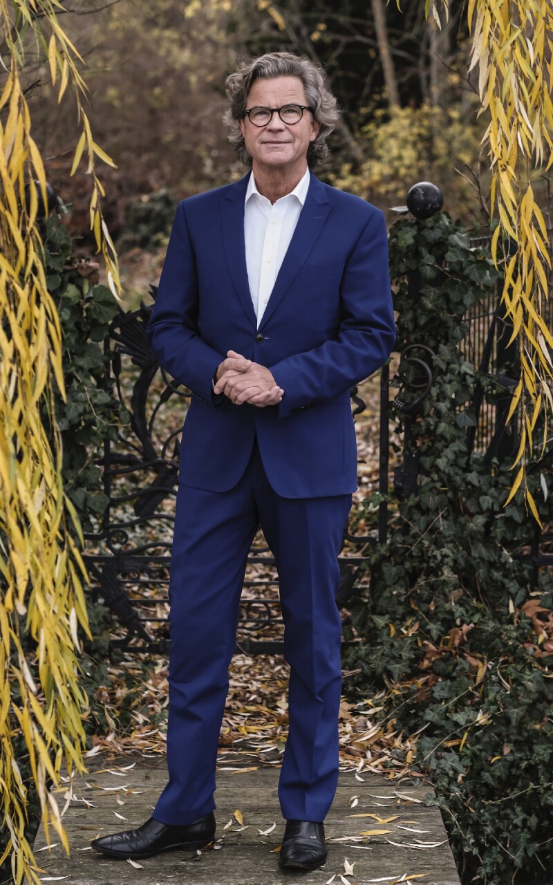 Das Foto zeigt Florian Langenscheidt, einen deutschen Verleger, Buchautor, Redner und Wagniskapitalgeber. Er steht in einem blauen Anzug im Freien.