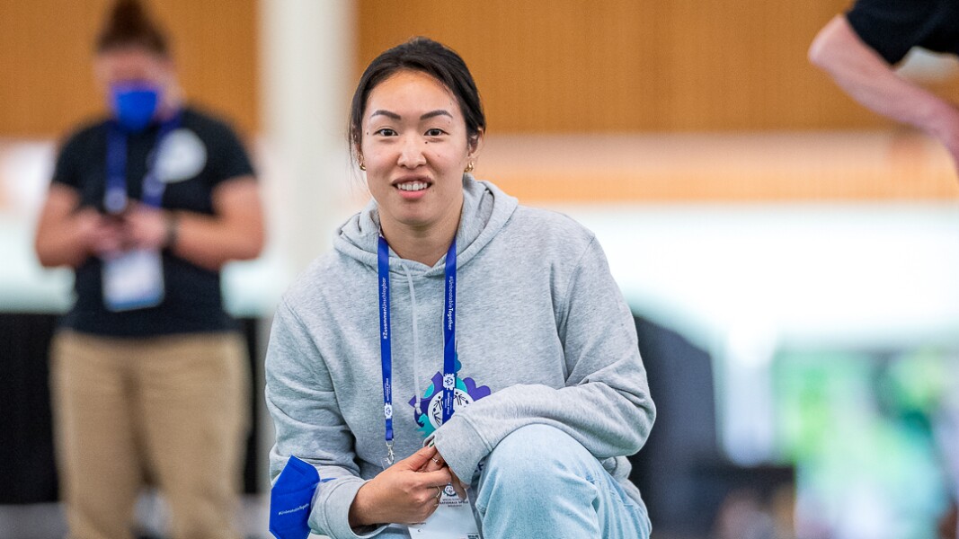 Auf dem Foto ist eine Athletin beim Boccia zu sehen. Sie guckt konzentriert aber leicht lächelnd und trägt einen grauen Pullover mit dem Logo der Nationalen Spiele.