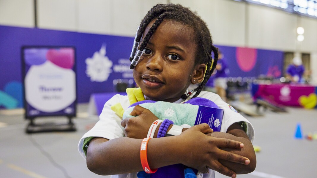 The photo shows a little girl who participated in the Young Athletes program during the World Games in Berlin, holding a plush Unity in her arms.