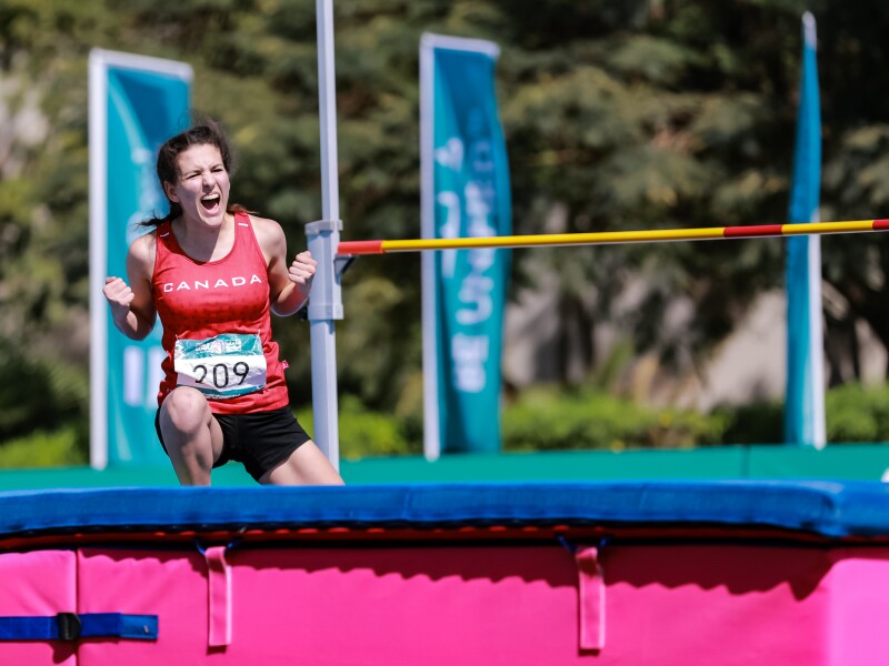 On the photo, there is a female athlete who just successfully did high jump.