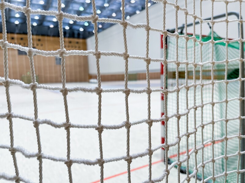 The photo shows a handball goal from behind with the focus on the net. 