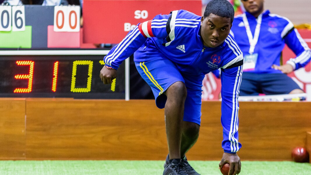 Auf dem Foto ist ein konzentrierter Boccia-Spieler, der gerade kurz davor ist, die Kugel loszulassen.