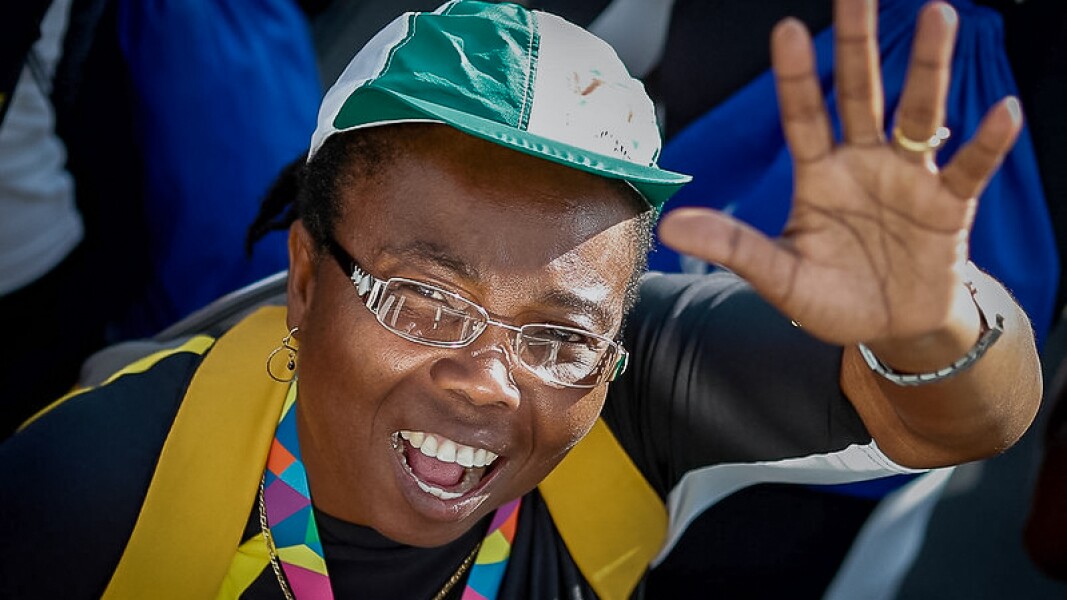 The photo shows a woman smiling and waving at the camera.
