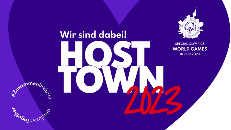 Die Grafik zeigt ein lilanes Herz auf dem "Wir sind dabei! Host Town 2023" steht. Außerdem ist unten links der Hashtag #ZusammenInklusiv sowie oben rechts das Weltspiele-Logo zu sehen.