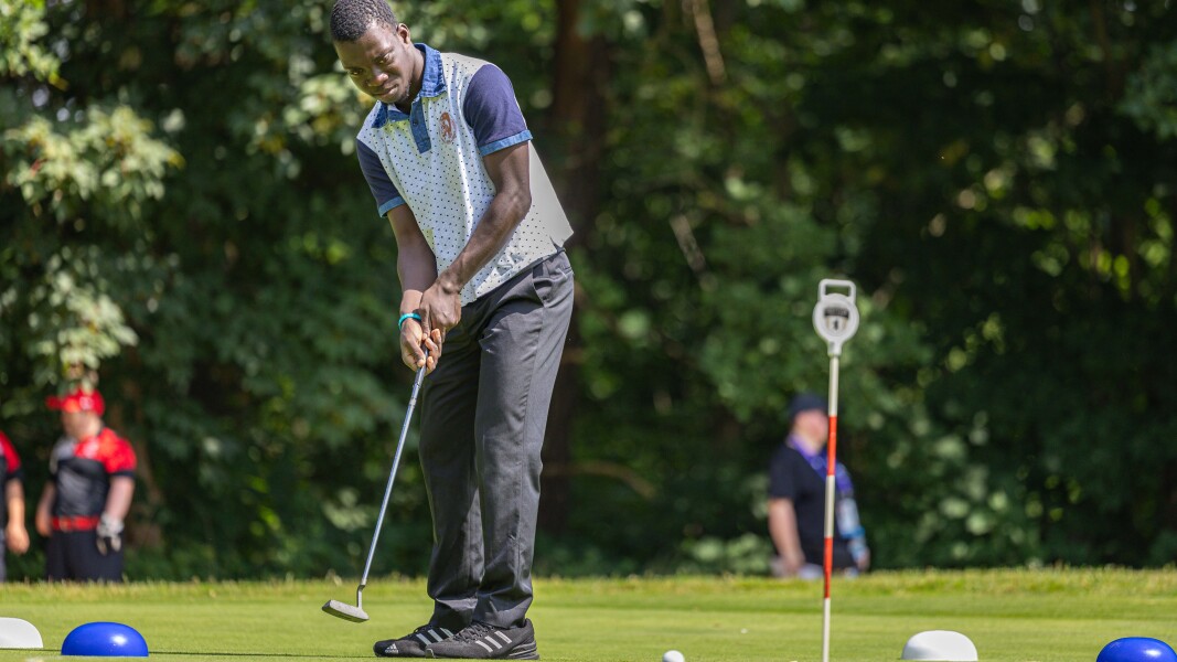 Ivory Coast male athlete Bekanty N´zue wearing white T-Shirt and black pants focussing to put the ball in the hole