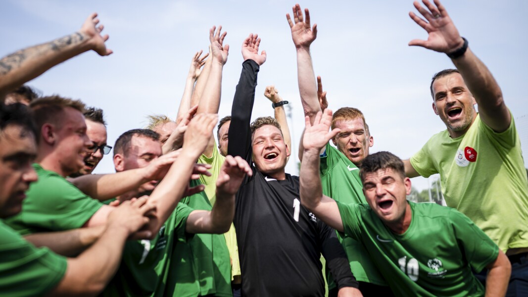 On the picture you can see a male futsal team smiling.
