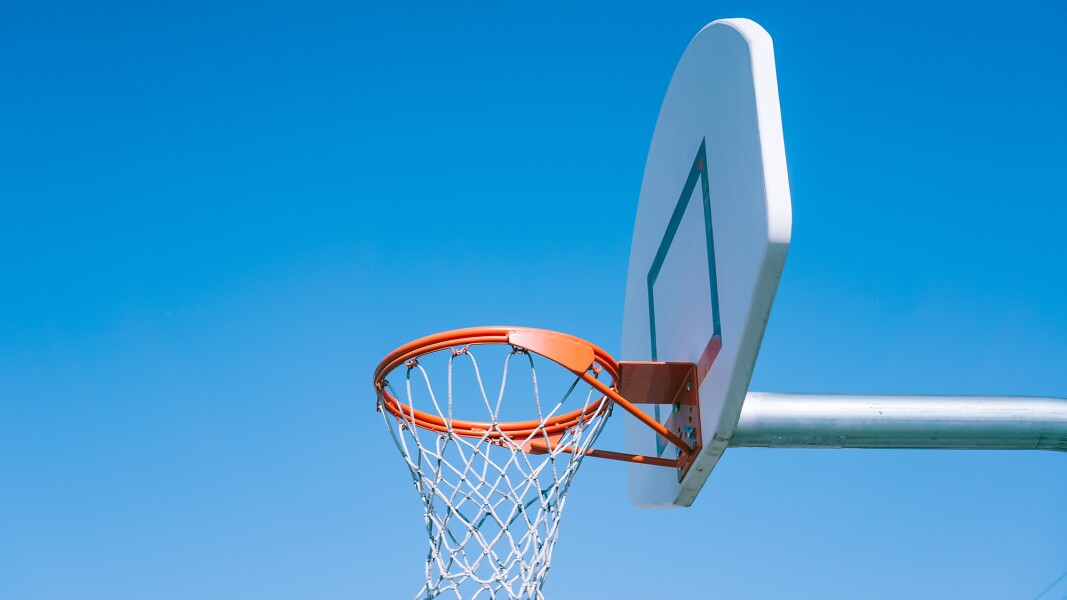 Auf dem Foto ist ein Basketballkorb im Freien vor blauem Himmel zu sehen.