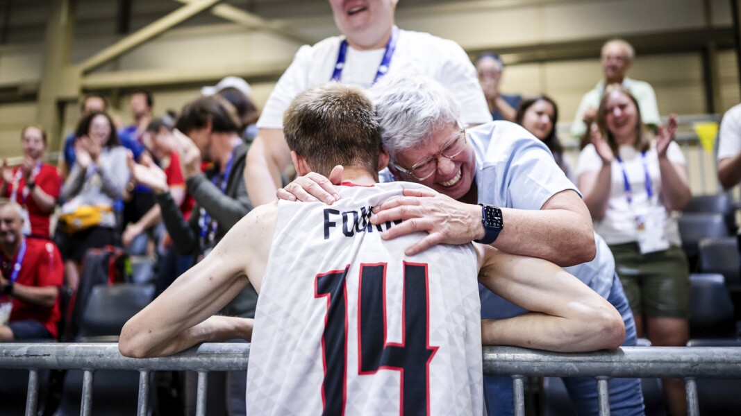 Das Foto zeigt einen Basketballspieler wie er eine Frau auf den Zuschauerrängen umarmt.