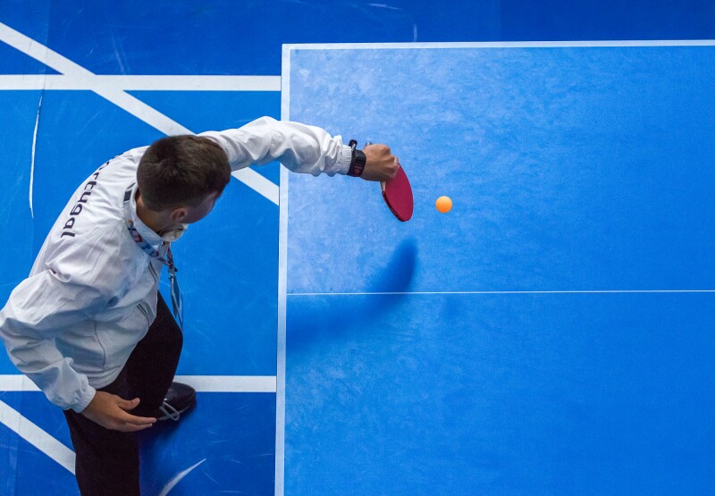 The photo is taken from above and shows an athlete while performing a table tennis stroke. 