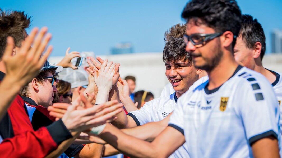 Das Foto zeigt das deutsche Fußball-Team. Es lässt sich von den Fans feiern und begrüßt diese mit Handschlag.