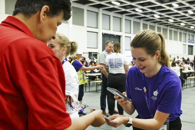 Das Foto zeigt einen Volunteers beim Scannen der Ausweise. Sie lächelt dabei.
