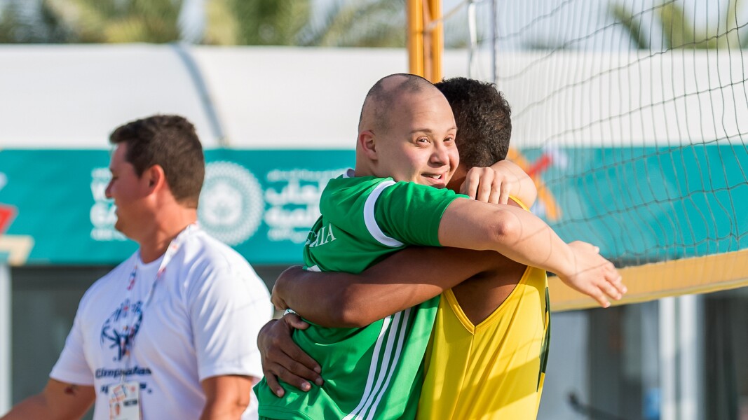 On the photo, there are two Beach Volleyball players holding each other in their arms.