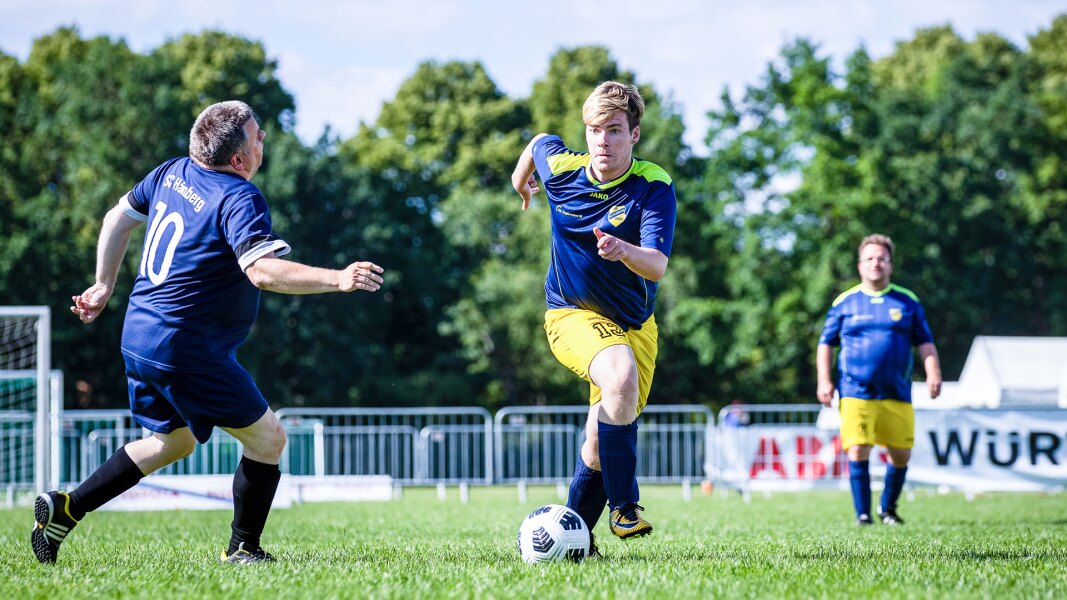The photo shows a football player running with the ball during competition.