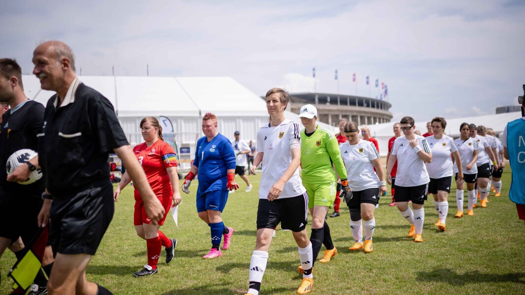 DE: Auf dem Bild laufen die Fussballmannschaften der Frauen aus Deutschland und Dänemark mit den Schiedrichtern gemeinsam ein.