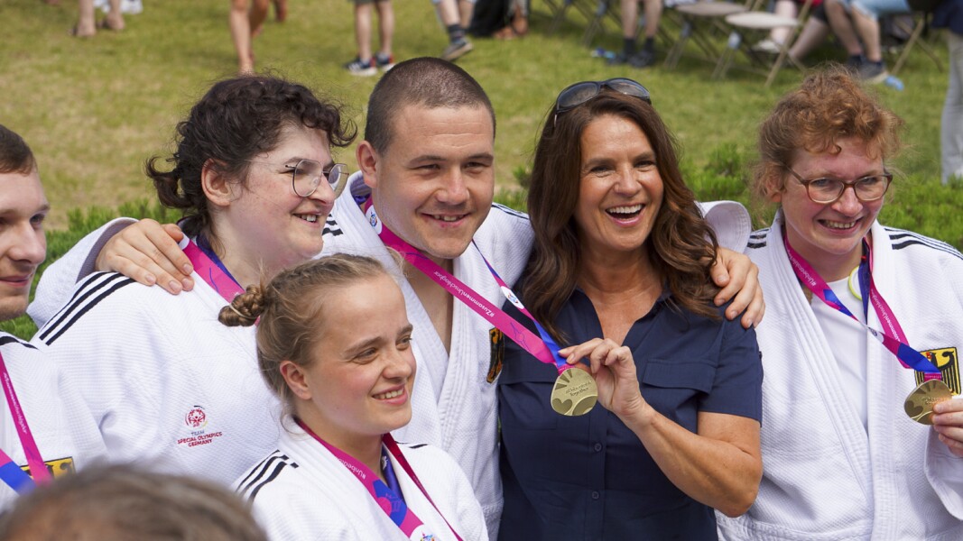 Auf dem Bild präsentieren die deutschen Judoka stolz ihre goldene Medaillie bei der Siegerehrung. Mit dabei ist die deutsche Eiskunstläuferin Katarina Witt.