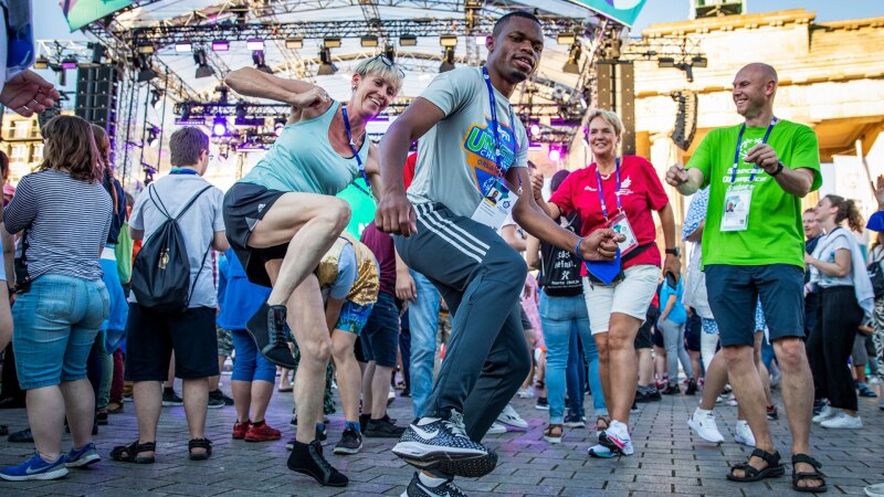 The photo shows a tant scene of different people during the athletes' party at the Brandenburg Gate.