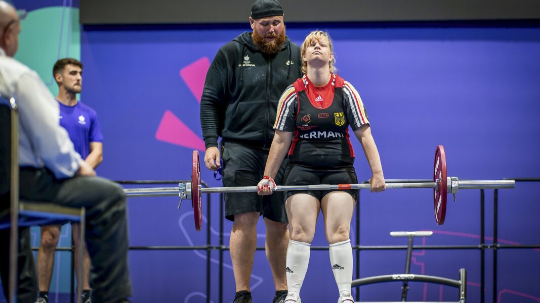 The photo shows a German woman doing powerlifting. She looks very relaxed and concentrated.