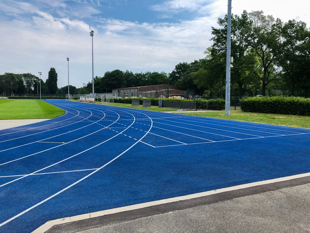 Das Foto zeigt eine blaue Laufbahn, die um eine Rasenfläche führt.