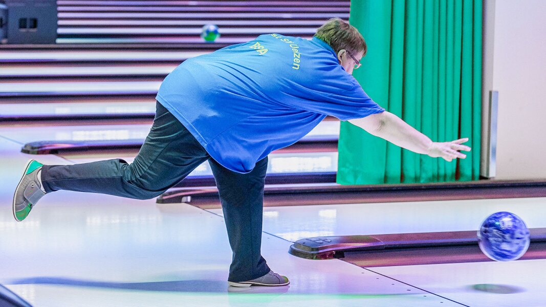 The photo shows an athlete in a bowling competition from the side and in action.