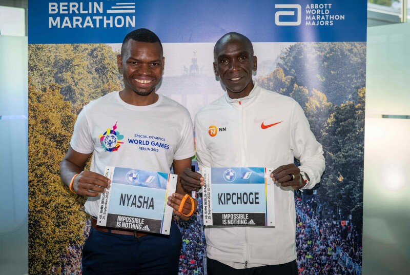 Auf dem Foto halten Special Olympics International Global Messenger und Langstreckenläufer Nyasha Derera und Olympiasieger und Vorbild Eliud Kipchoge ihr jeweiliges Marathon-Namensschild lächelnd in die Kamera.