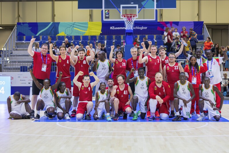 Im Bild zwei Basketball-Teams bunt untereinander gemischt nach dem Spiel. 