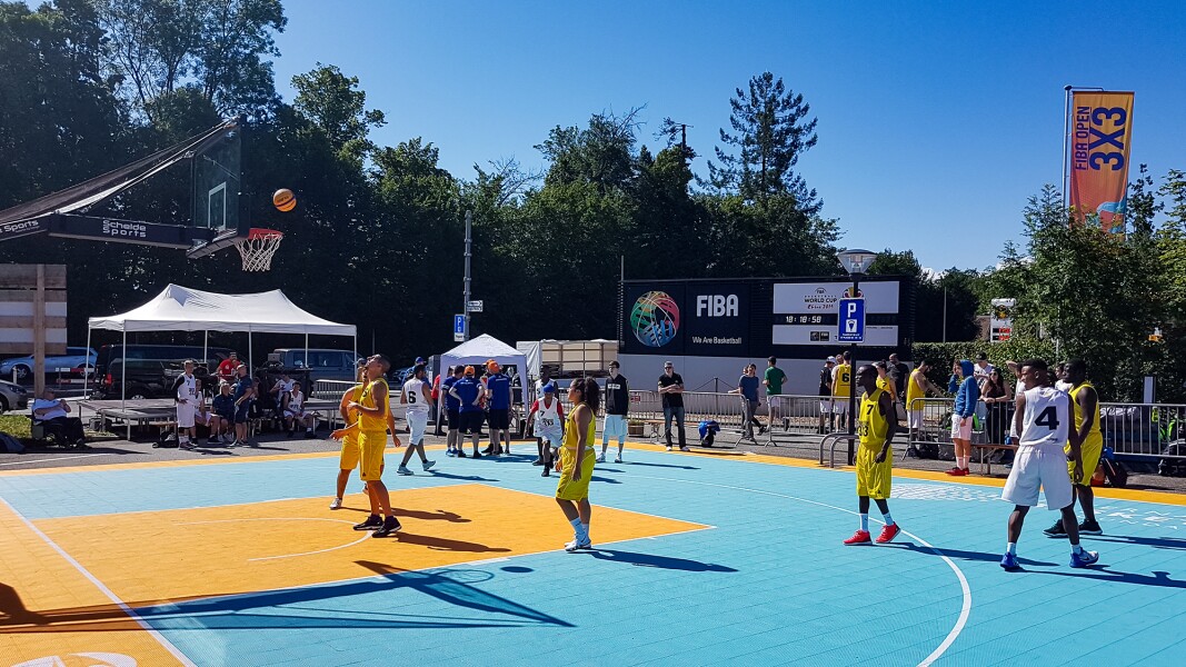 Das Bild zeigt einen 3x3 Basketballplatz mit zwei Teams im Freien.