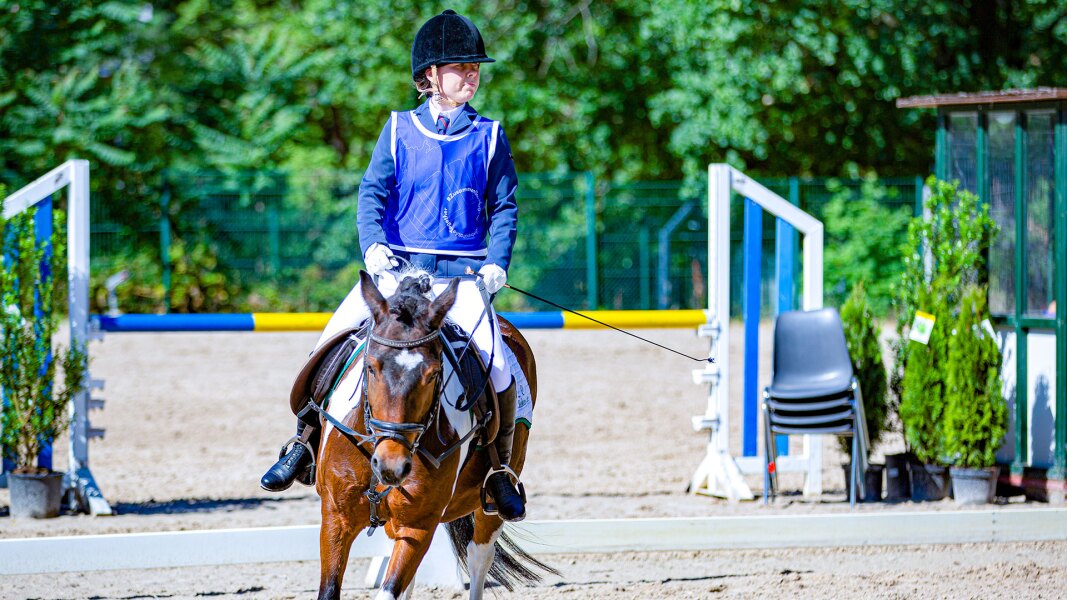 The photo shows an athlete on her horse during the show jumping competition.