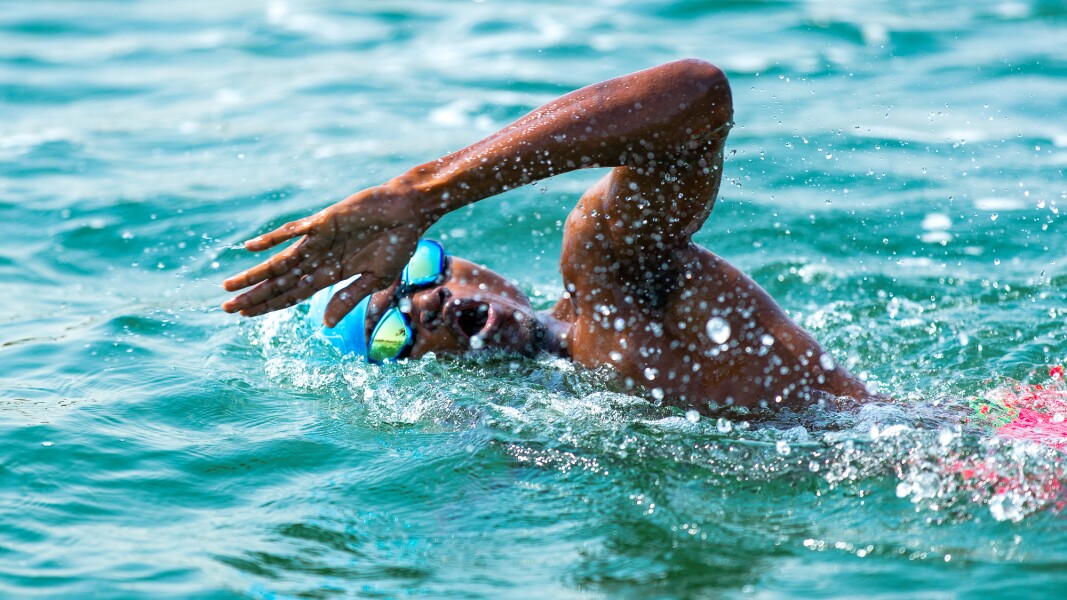 Das Foto zeigt eine Athletin beim Freiwasserschwimmen. Wasser spritzt, während sie krault.