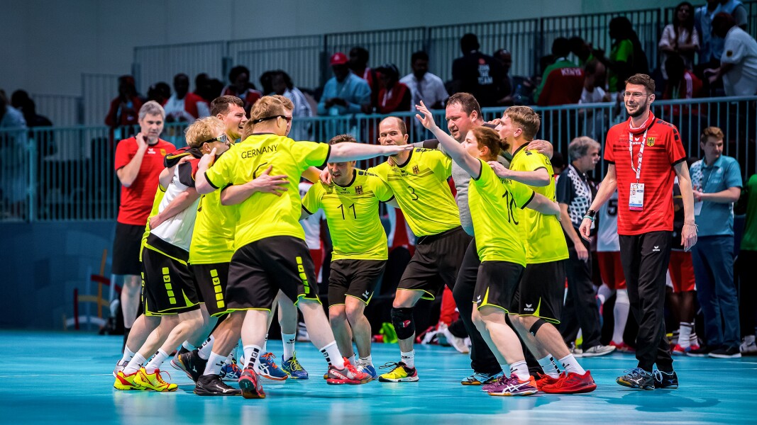 Das Foto zeigt die deutsche Handballmannschaft in Abu Dhabi. Sie jubeln im Kreis und freuen sich.