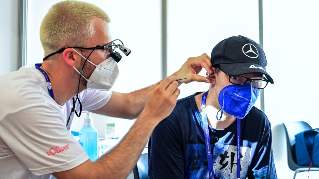 The photo shows an ear examination of an athlete at the Healthy Athletes Program at the Berlin 2022 National Games. The doctor is about to look into the athlete's ear.