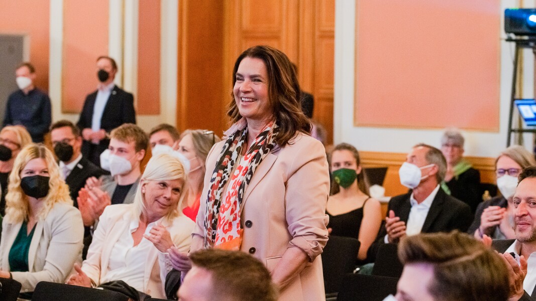 The picture shows Katarina Witt, former figure skater and chairwoman of the Katarina Witt Foundation, smiling as she delivers a speech.