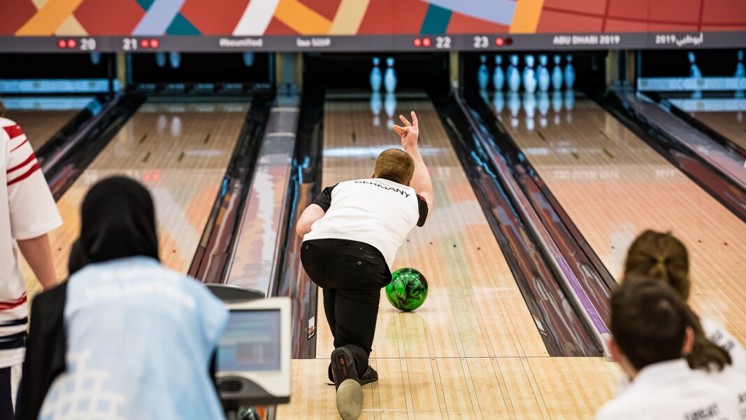 Das Foto zeigt einen Bowling-Spieler von hinten, der gerade seine Kugel auf den Weg zu den zwei verbleibenden Kegeln geschickt hat.