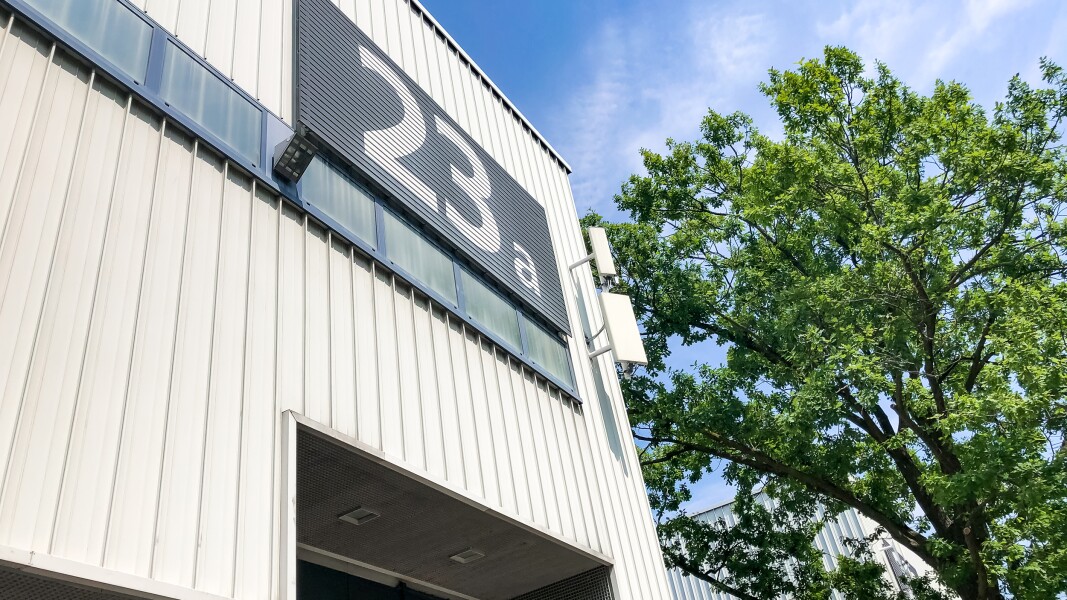 The photo shows a part of a large white hall with the inscription 23a.