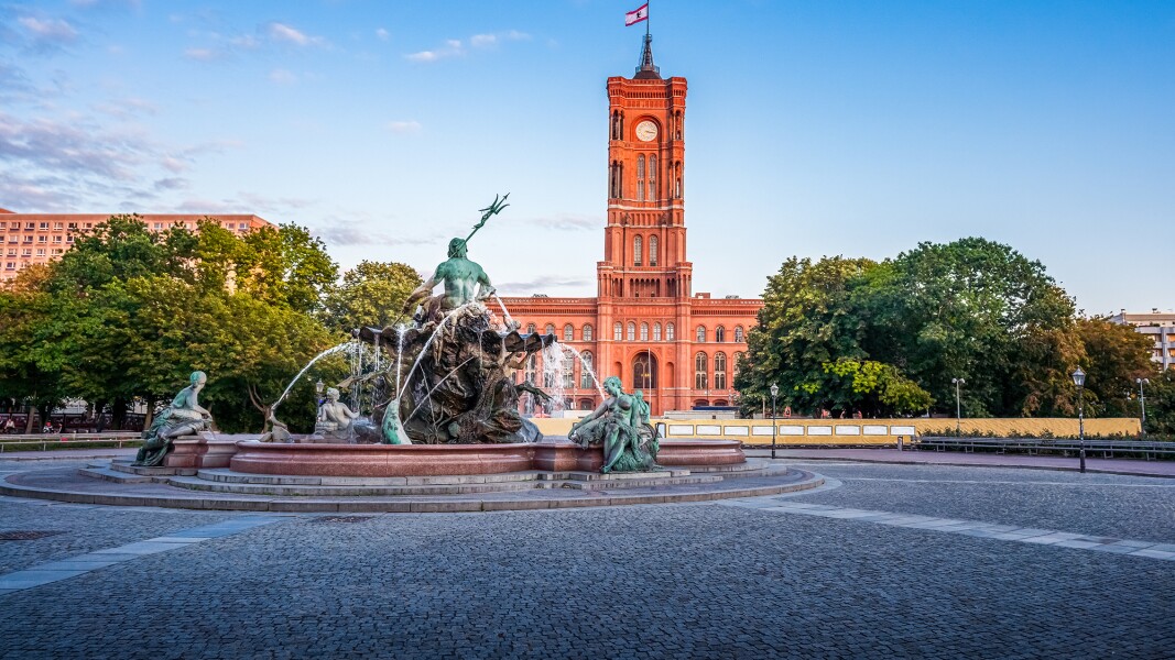 Das Foto zeigt den aktiven Neptunbrunnen und das Rote Rathaus in Berlin im Hintergrund.