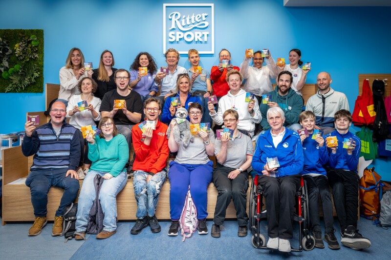 The photo shows many athletes and also Friends of the Game. They are holding up a Rittersport and enjoying themselves.