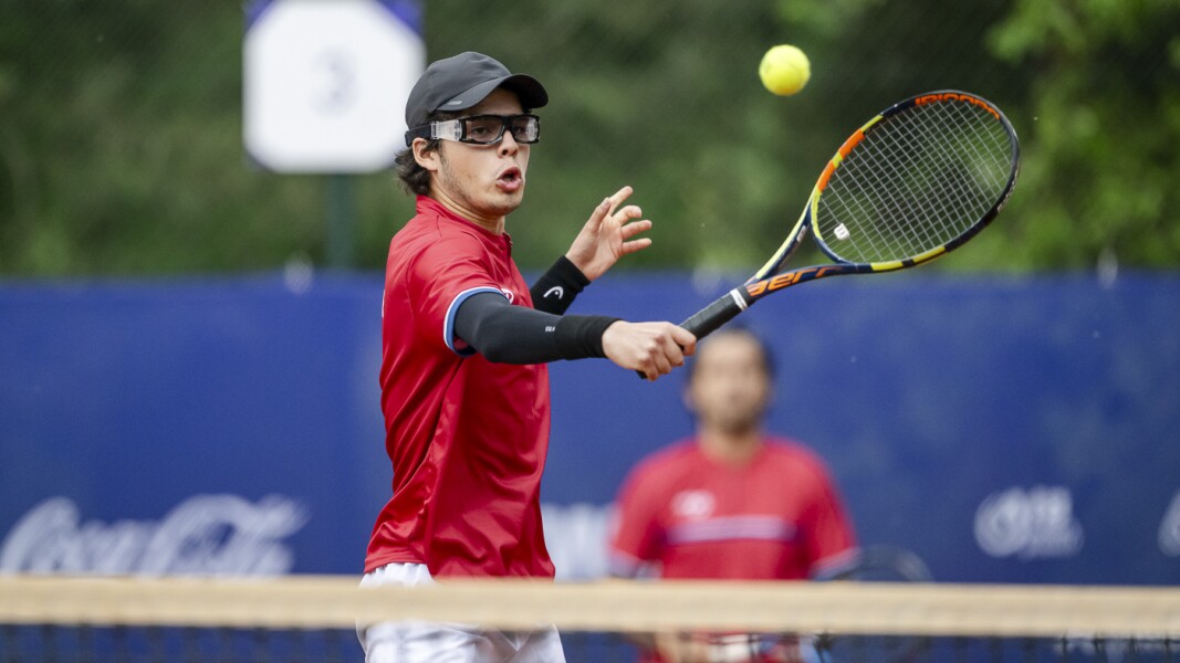 In the photo there is a tennis player from SO Chile. He is standing at the net and playing a volley.