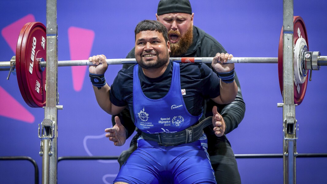 The photo shows an athlete doing powerlifting. He looks concentrated.
