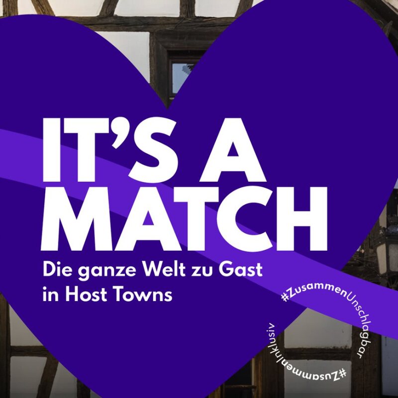 Die Grafik beinhaltet ein Herz, auf dem steht: "It's a match! Die ganze Welt zu Gast in Host Towns" und der Hashtag #ZusammenUnschlagbar.