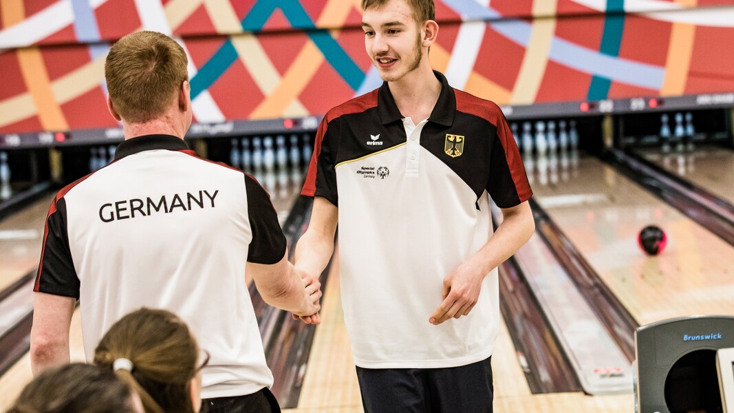 Auf dem Foto sind zwei Bowling-Spieler zu sehen, die sich gerade im Wettkampf die Hände geben beziehungsweise abklatschen.