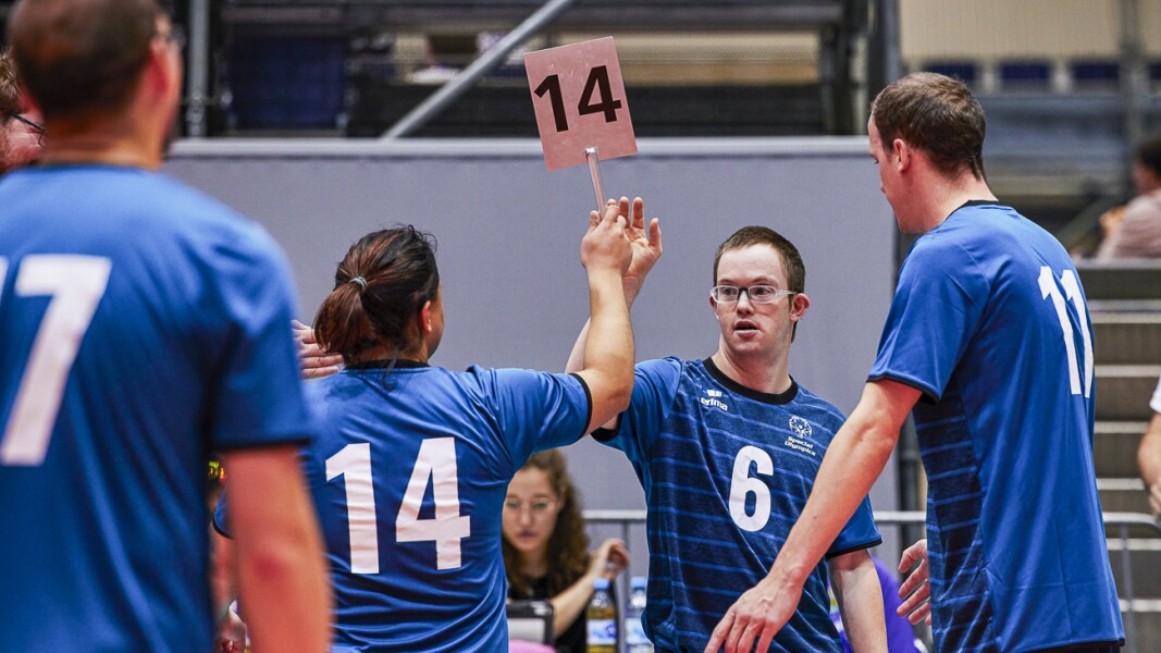 Auf dem Foto sieht man eine Szene beim Volleyball, in der gerade ein Wechsel von Spieler*innen stattfindet.