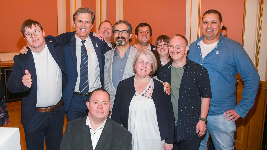 Das Foto zeigt eine Gruppe von Menschen, die gemeinsam in die Kamera lächelt. Mitten drin ist Timothy Shriver, der Chairman von Special Olympics International.