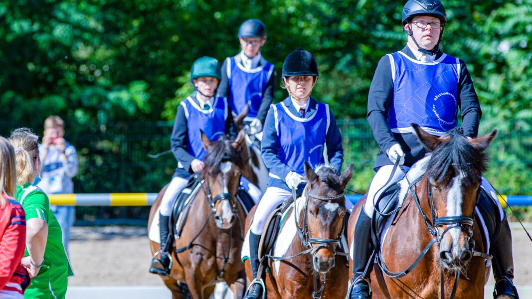 Auf dem Foto sieht man 4 Athletinnen und Athleten auf ihren Pferden.
