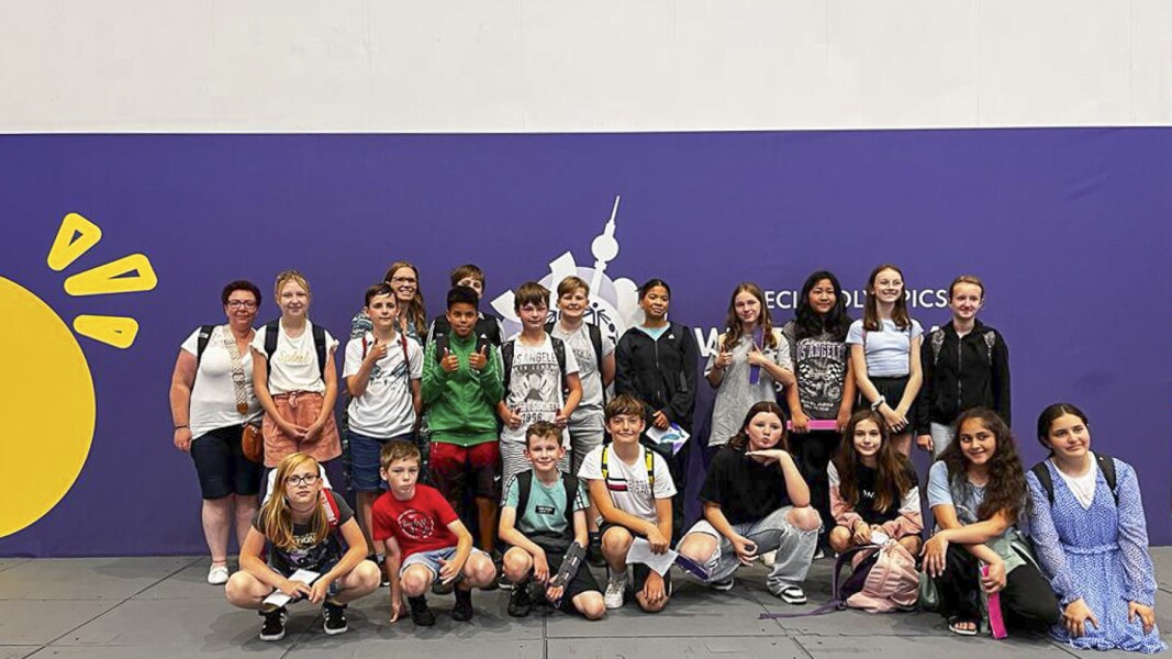 The photo shows an primary school class at the Fands in the Stands program. They are standing in two rows and enjoying themselves.