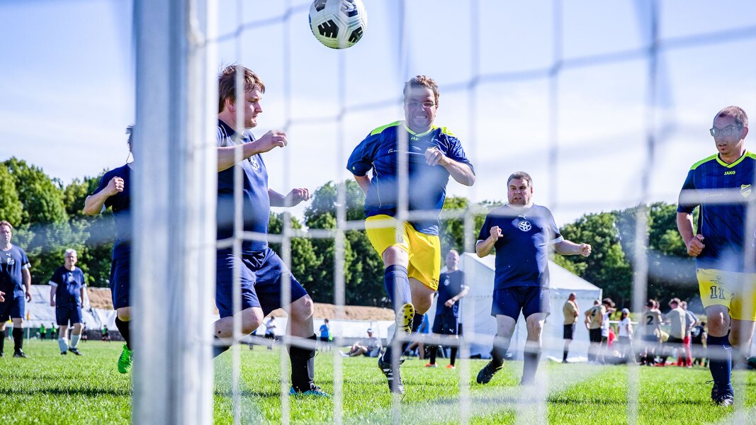 The photo shows a football action scene. It was taken from behind the goal so the net is visible.