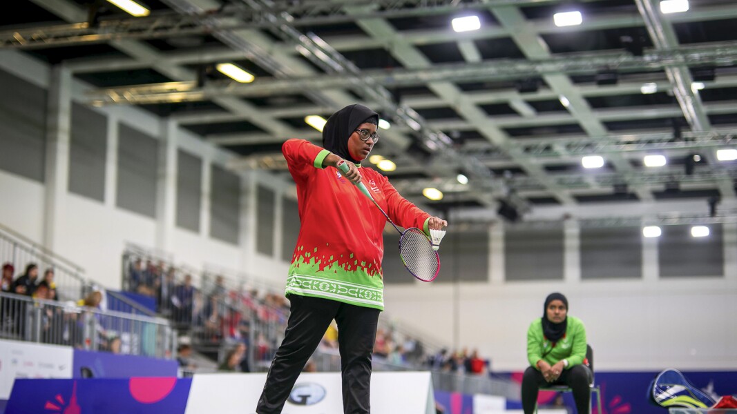 Das Foto zeigt eine Badminton-Spielerin kurz vor ihrem Aufschlag. Sie schaut sehr konzentriert.