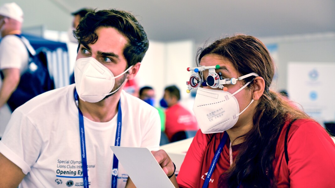 On the picture you see a man and a woman during an Healthy Athletes eye examination, an athlete is doing an eye test.