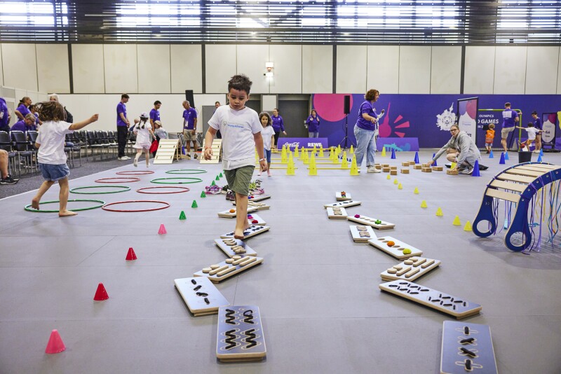 Kids testing their skills in sport games, jumping through loops and various barriers set up by the volunteering stuff