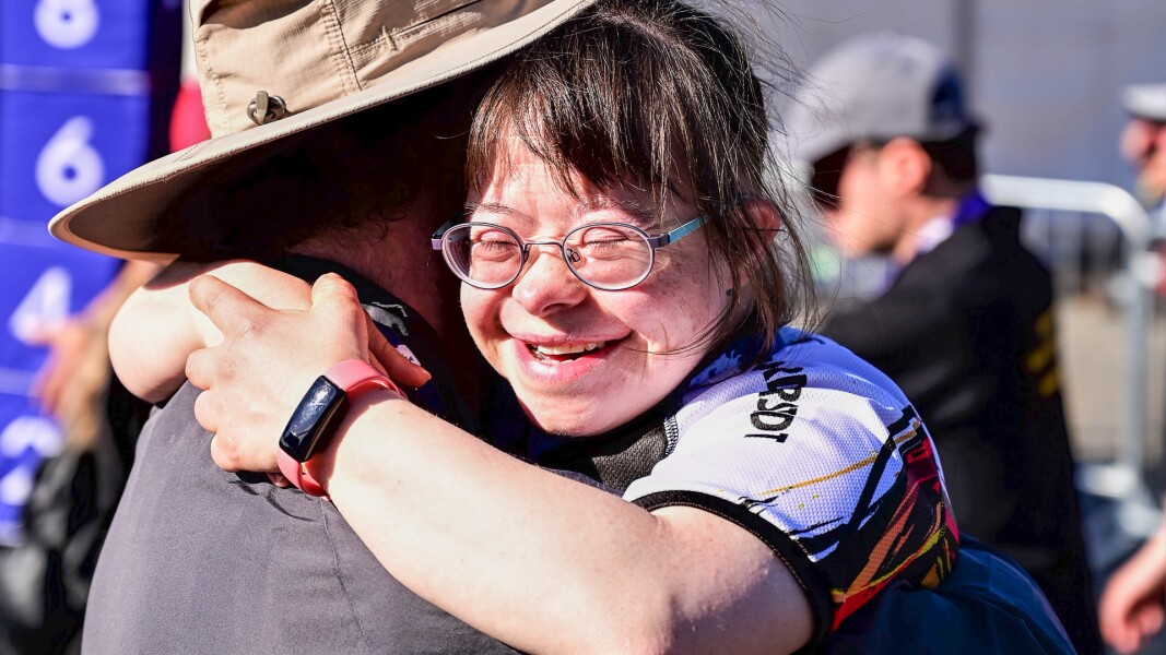 On the photo, there is a cyclist hugging another person with joy after finishing her competition successfully.
