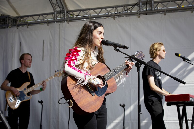 Das Foto zeigt eine Band, die auf dem Special Olympics Festival 2022 auftritt. Im Vordergrund ist die Sängerin zu sehen, die mit ihrer Gitarre auf der Bühne steht.