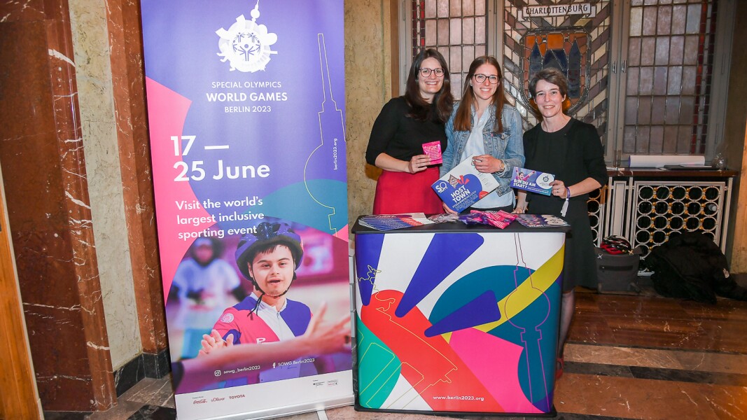 Das Foto zeigt den Empfang im Roten Rathaus in Berlin, bei dem Mitarbeiterinnen des LOC mit bunt gebrandeten Materialien bereit stehen. Sie lächeln fröhlich in die Kamera und präsentieren sden Gästen unsere Events.